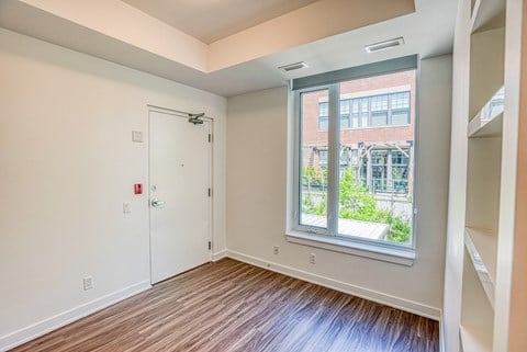an empty room with a large window and wood flooring
