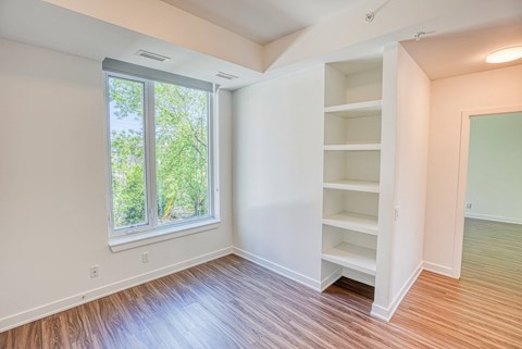 an empty room with wood flooring and a large window
