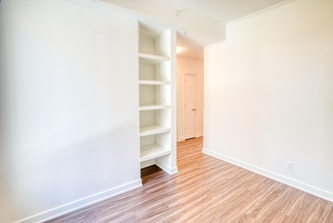 an empty room with white shelves and a wood floor