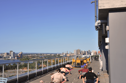 people laying out on the roof of a building with a city in the background