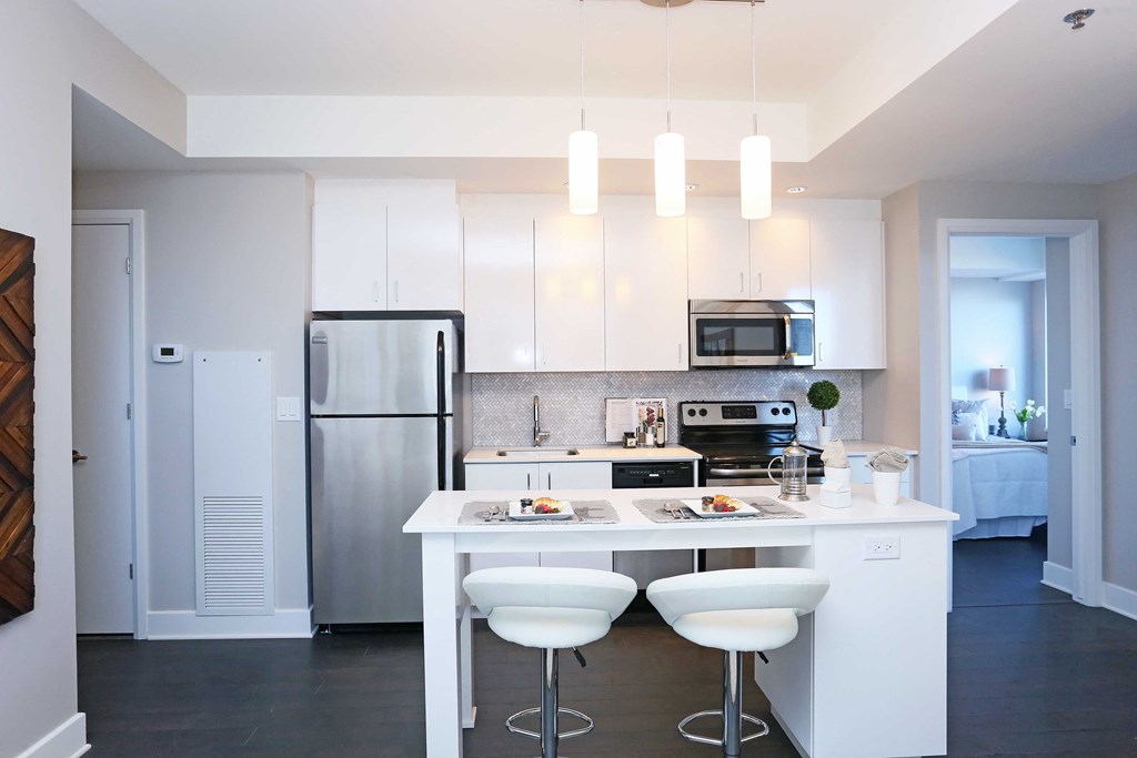 a kitchen with white cabinets and a white island with white chairs