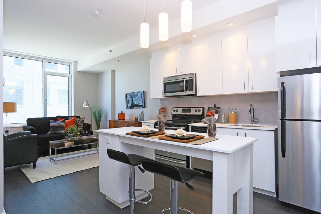 a kitchen with a white island and a stainless steel refrigerator