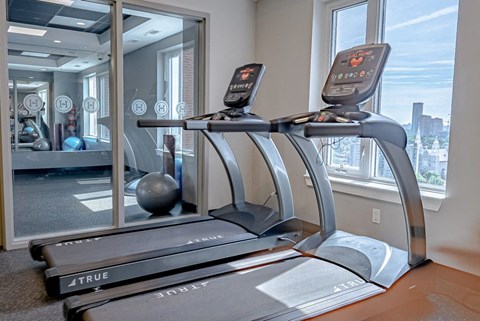 the gym has a treadmill and a view of the city