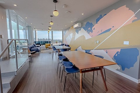 a communal area with tables and chairs and a mural on the wall