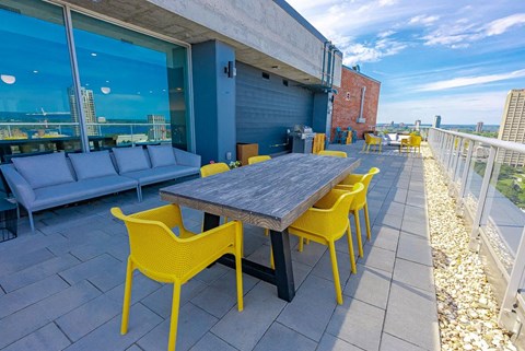 a patio with a wooden table and yellow chairs