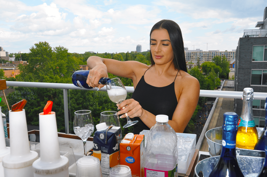 a woman pouring wine into a glass on a balcony