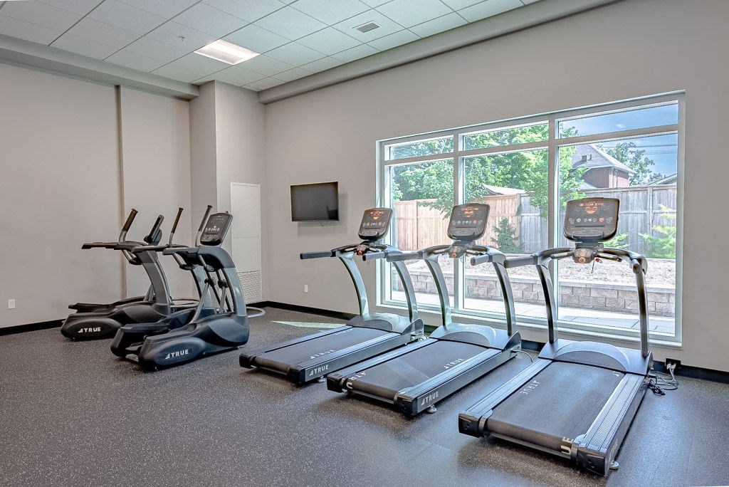a gym with cardio equipment and a large window