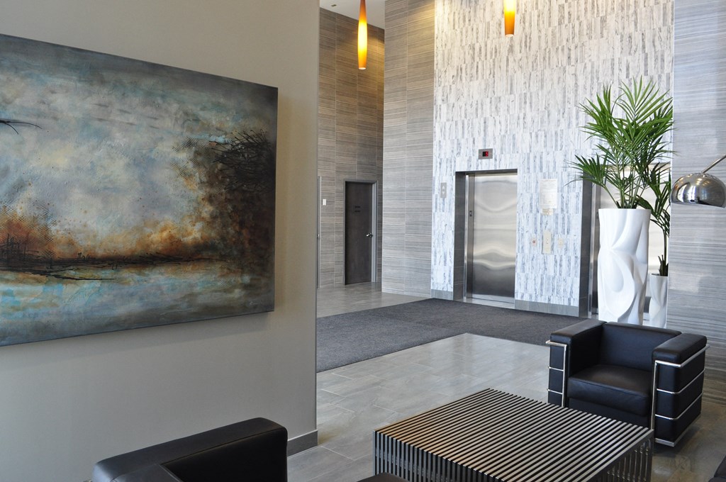 a lobby with a painting on the wall and a table and chairs