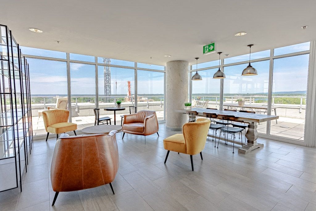 a lobby with chairs and tables and a view of a refinery