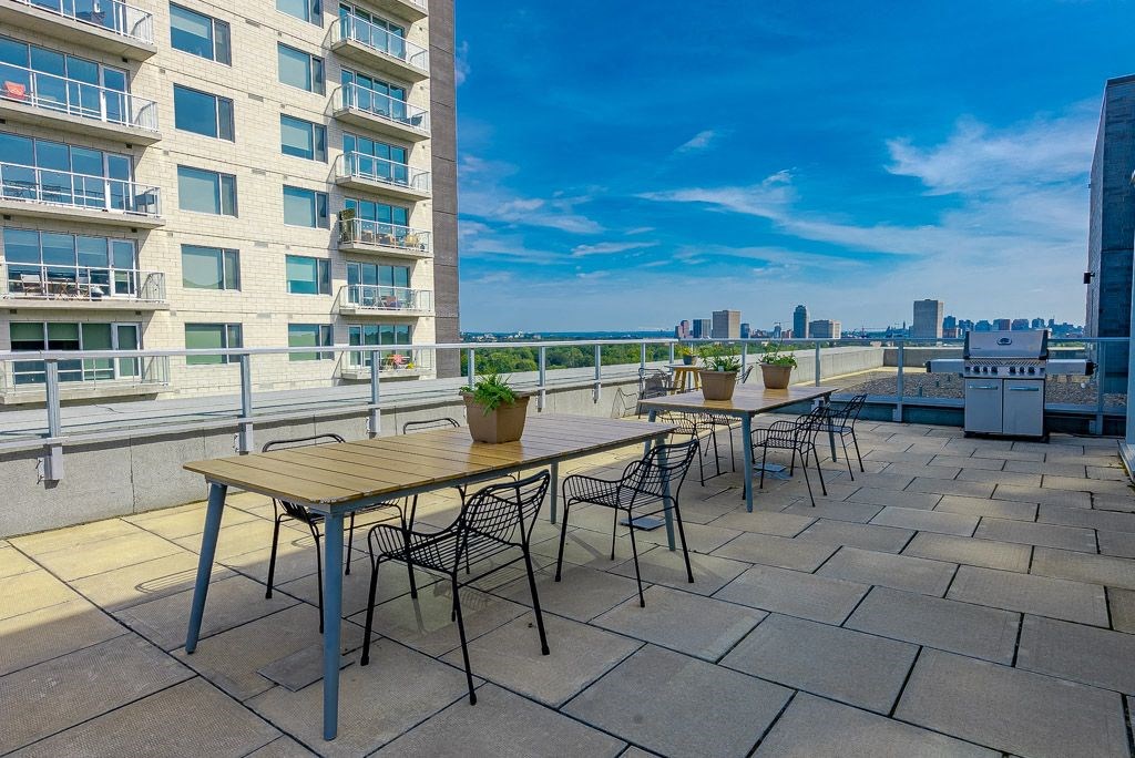 a rooftop patio with tables and chairs and a view of the city