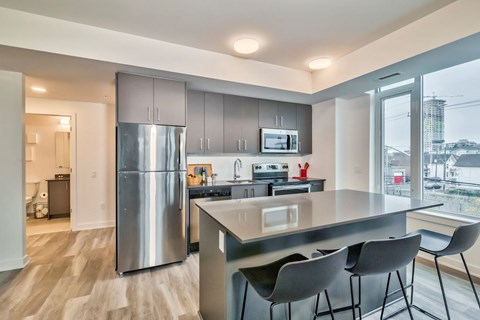 a kitchen with stainless steel appliances and a counter with three chairs