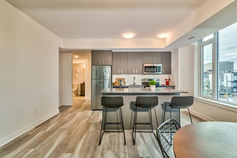 a kitchen with a bar and three stools in front of a large window
