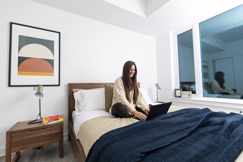 a woman sitting on a bed with a laptop