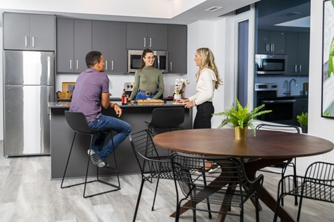 three people in a kitchen with a table