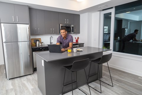 a man sitting at a kitchen counter using a laptop computer