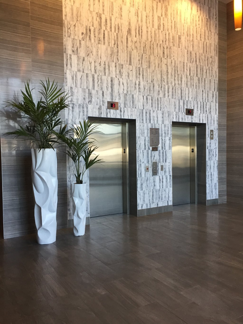 a lobby with two potted plants in front of the elevators