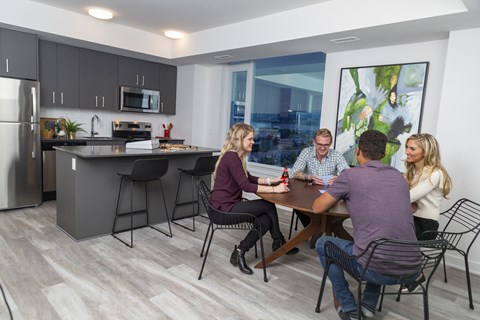 a group of people sitting around a table in a kitchen
