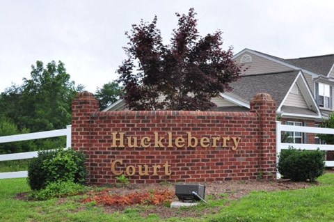 A sign that says Huckleberry Court in front of a house.