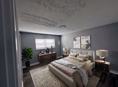 A bedroom with a large bed and a potted plant.