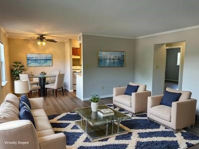 A living room with a glass coffee table and two beige chairs.