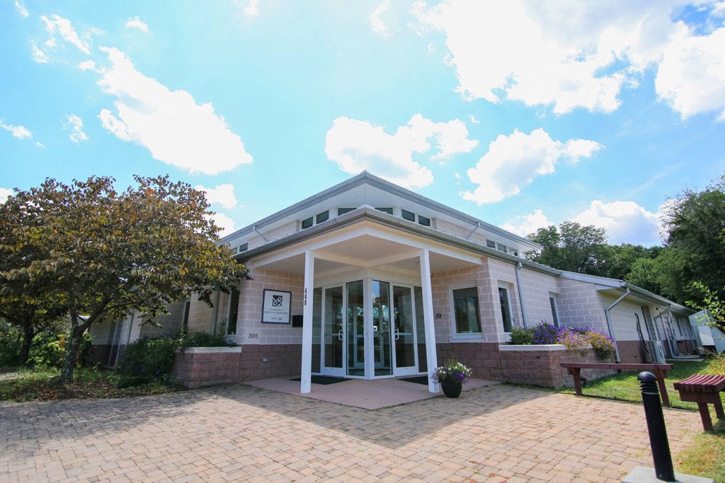 the front of a white house with a brick sidewalk and a porch