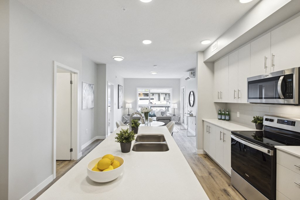 an open kitchen and living room with white cabinets and a white counter top with a