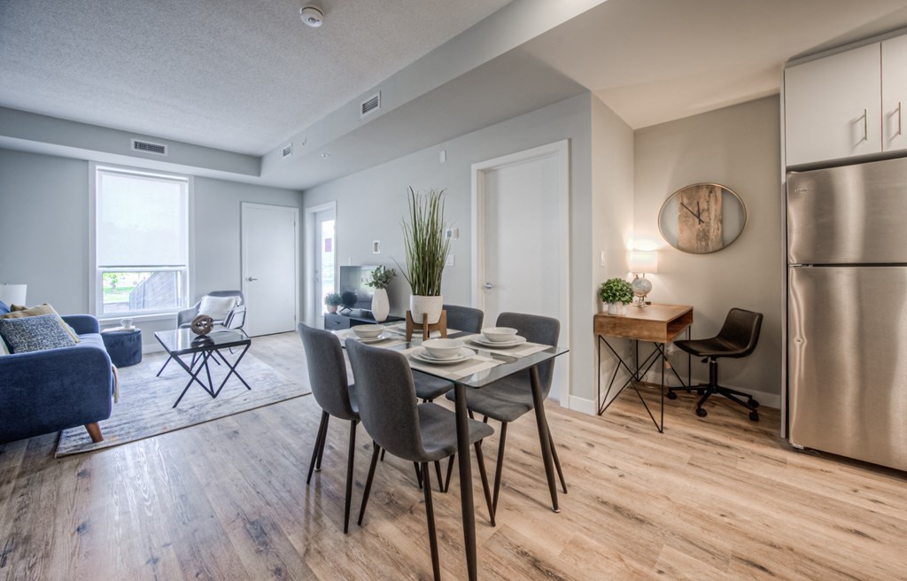 a dining area with a table and chairs and a stainless steel refrigerator