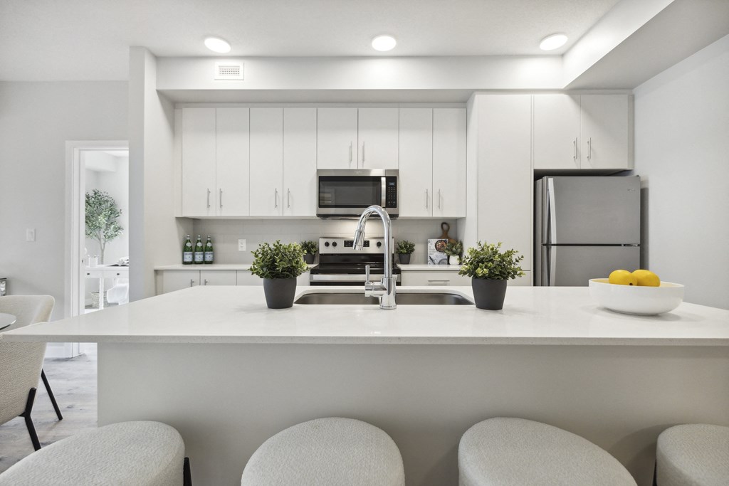 a modern kitchen with white cabinets and a white counter top with a sink
