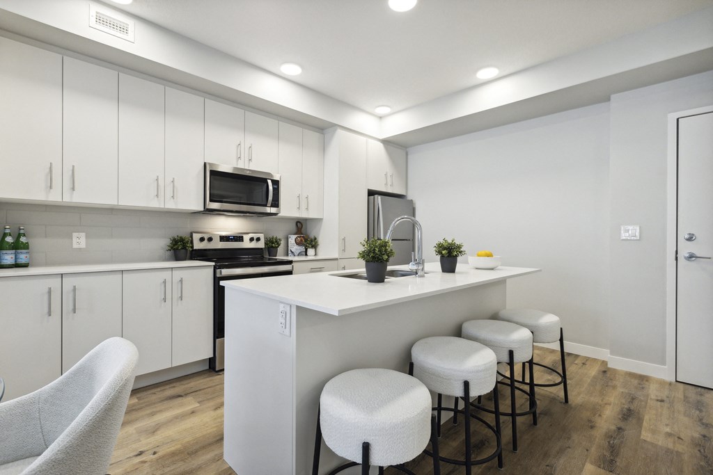 a kitchen with white cabinets and a counter with stools