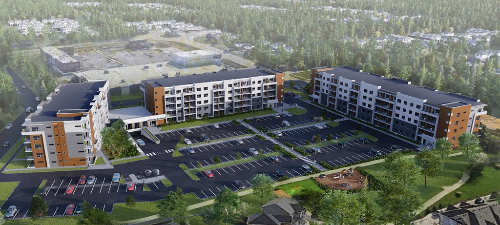 an aerial view of a large apartment complex with a parking lot and a forest in the background