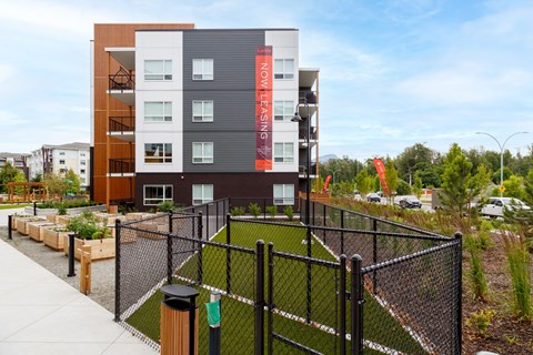A modern apartment complex with a fenced in yard.