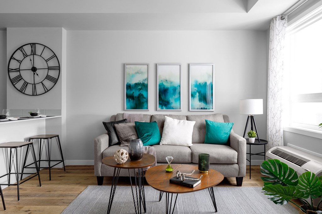 a living room with a gray couch and turquoise pillows