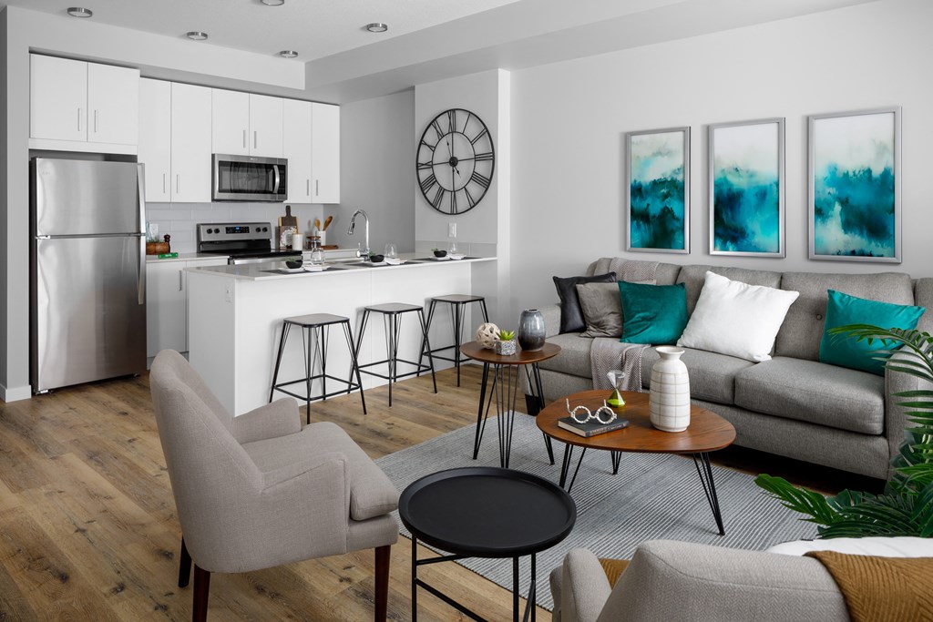 a living room with a kitchen in the background and a couch and chairs in the foreground