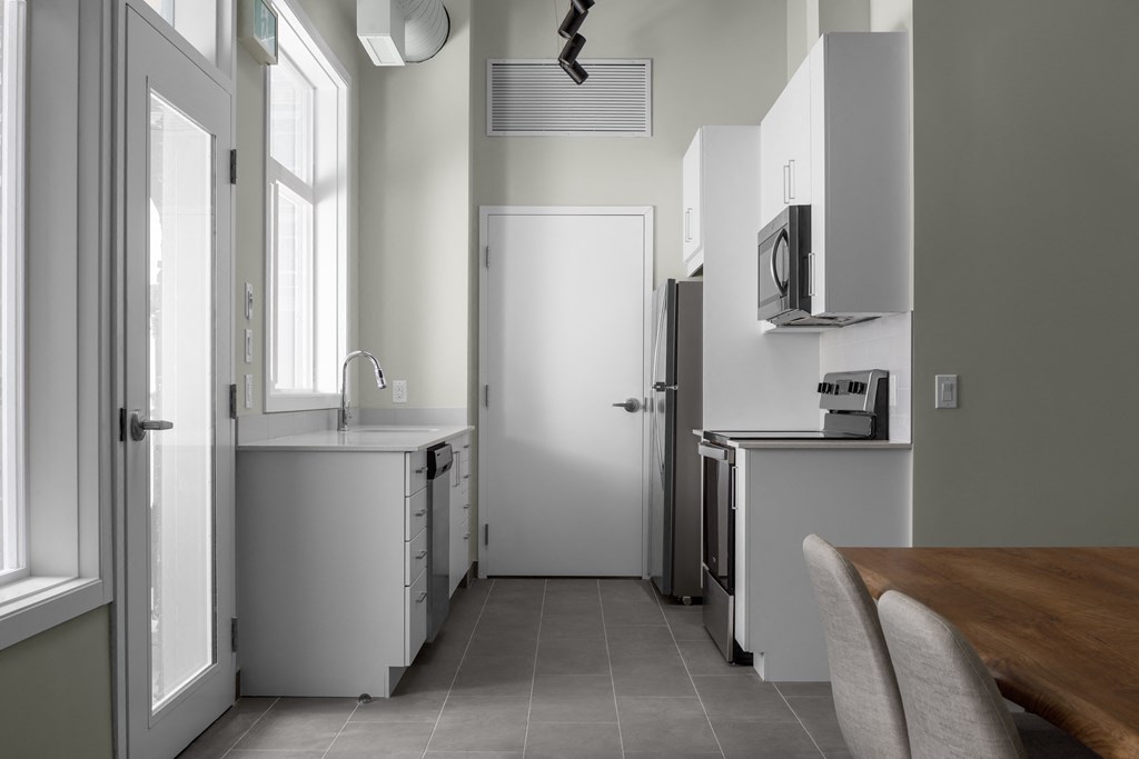 a small kitchen with white cabinets and a wooden table