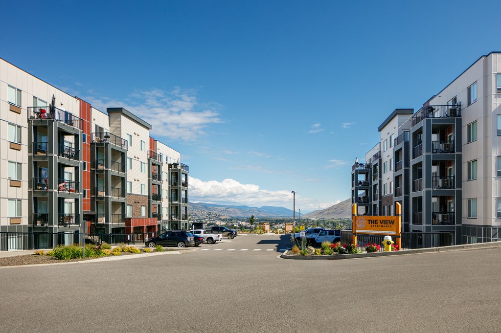a city street with buildings on either side and mountains in the background