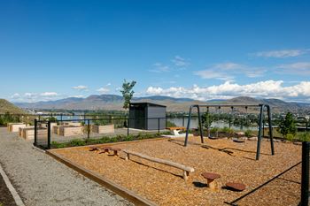 A playground with a swing set and a tree in the background.