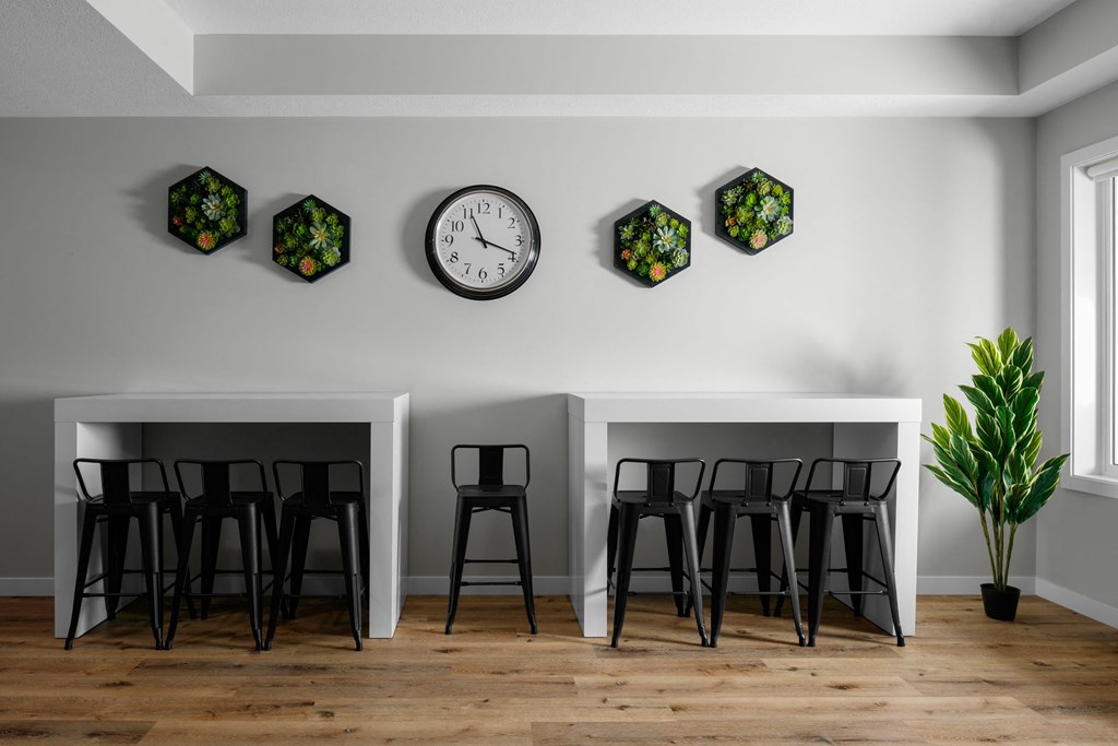 two tables and three stools in a room with a clock on the wall