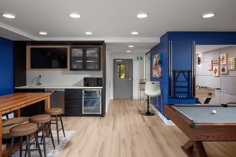 A room with a pool table and a bar area.