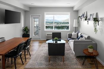 A living room with a couch, chairs, a coffee table, and a flat-screen TV.