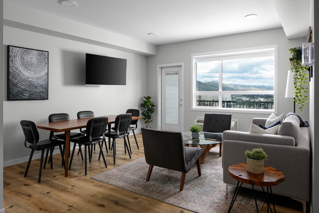 a living and dining area with a table and chairs and a flat screen tv on the wall