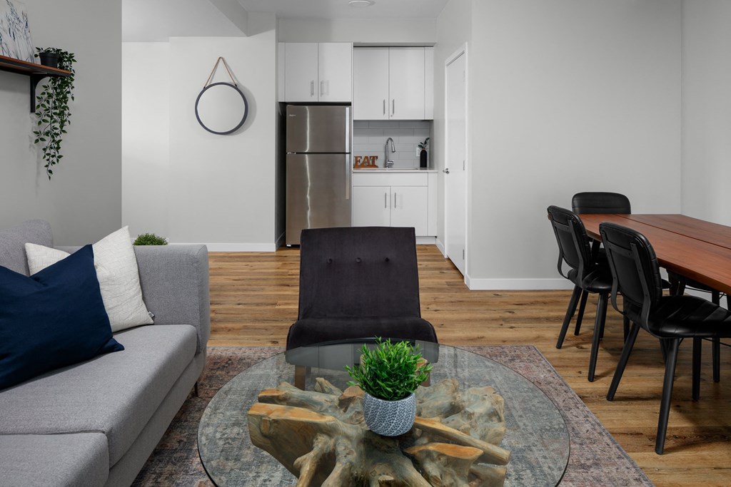 a living room with a couch a table and chairs and a kitchen in the background
