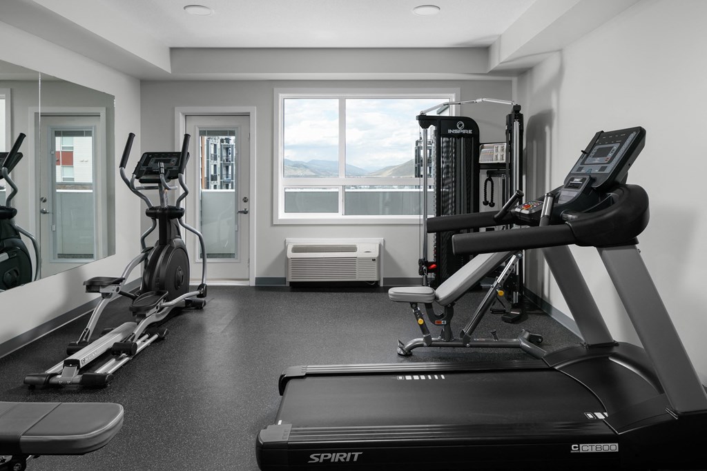 A black and white photo of a gym with a treadmill in the foreground.