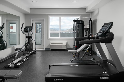 A black and white photo of a gym with a treadmill in the foreground.
