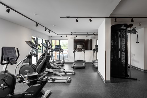 A black and white photo of a gym with a row of exercise bikes.