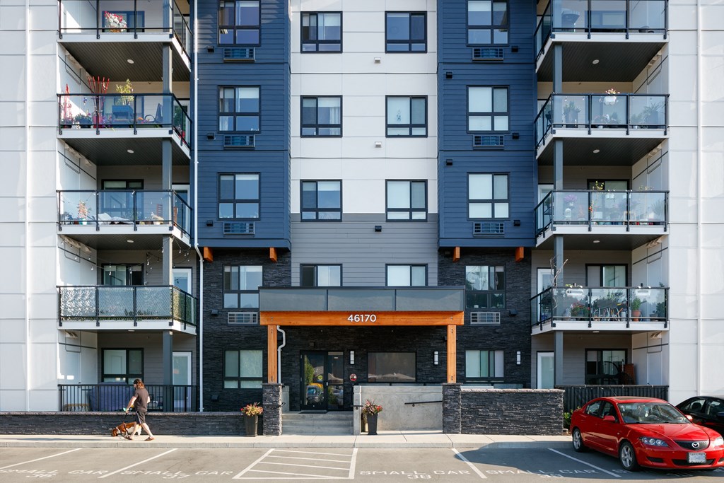 a woman walks her dog in front of an apartment building
