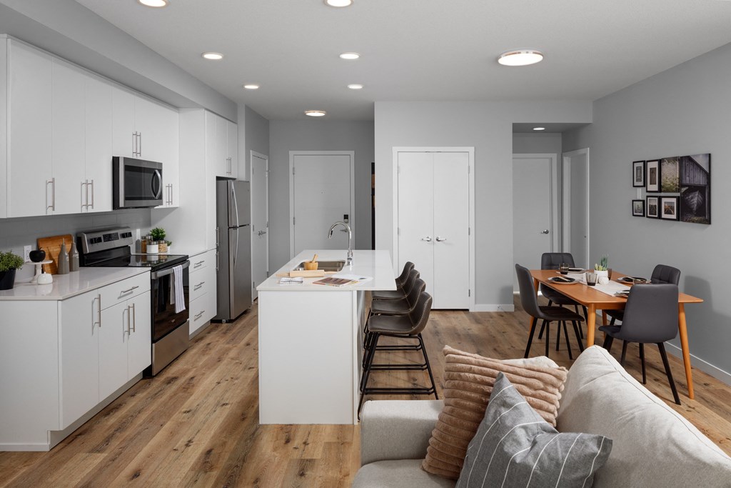 a kitchen and living room with white cabinets and a table and chairs