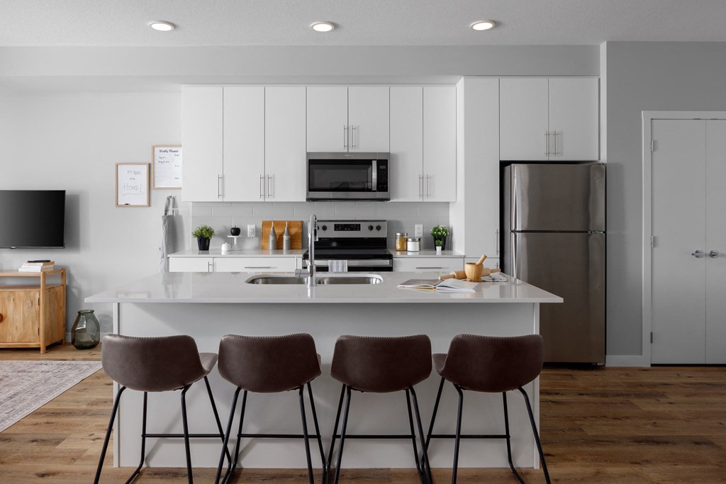 a kitchen with white cabinets and a counter with four chairs