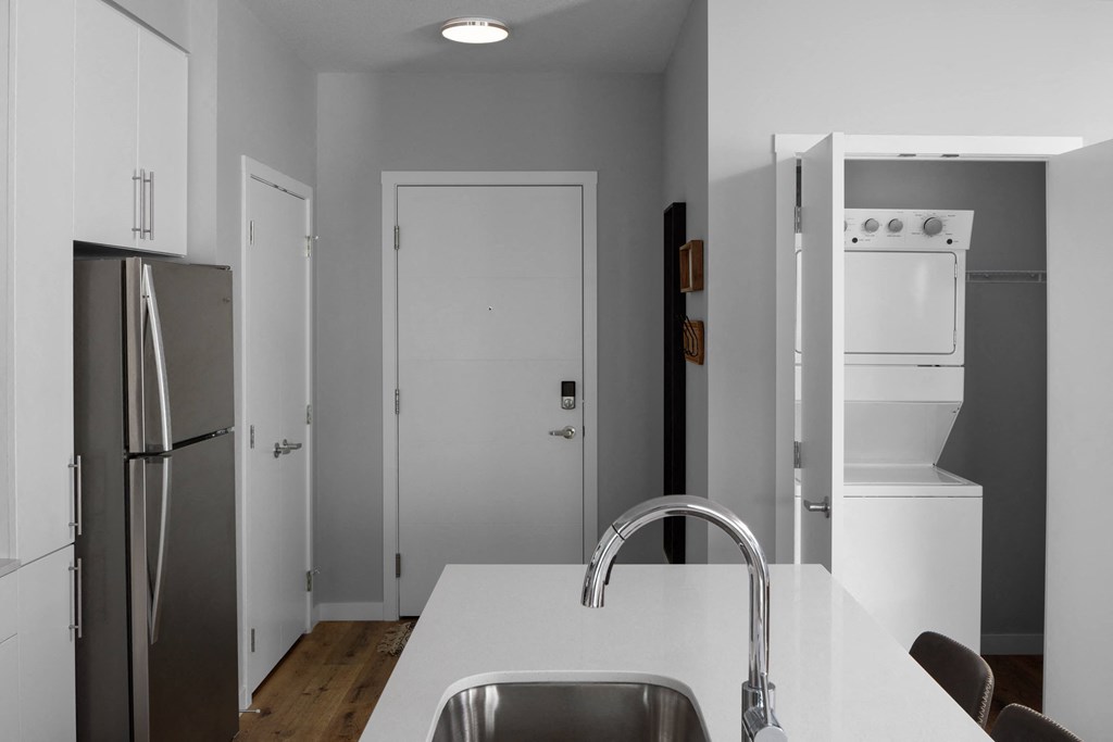 a kitchen with a white counter top and a stainless steel refrigerator