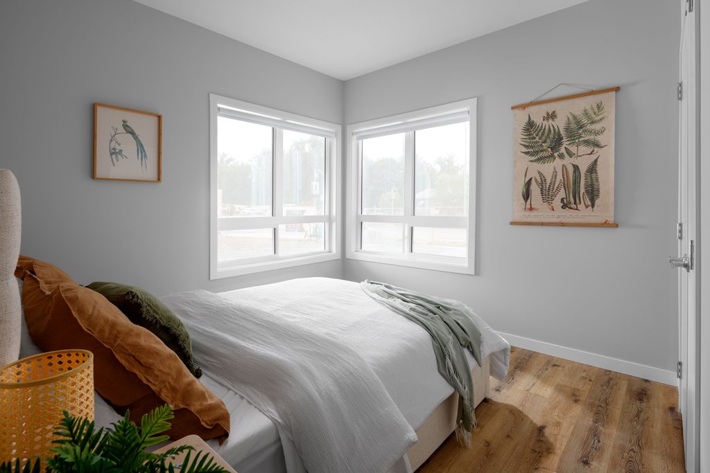 A bedroom with a bed, pillows, a basket, and two wall hangings.
