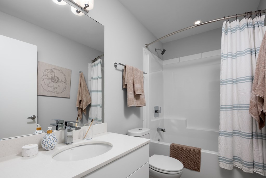 A bathroom with a toilet, sink, and shower.